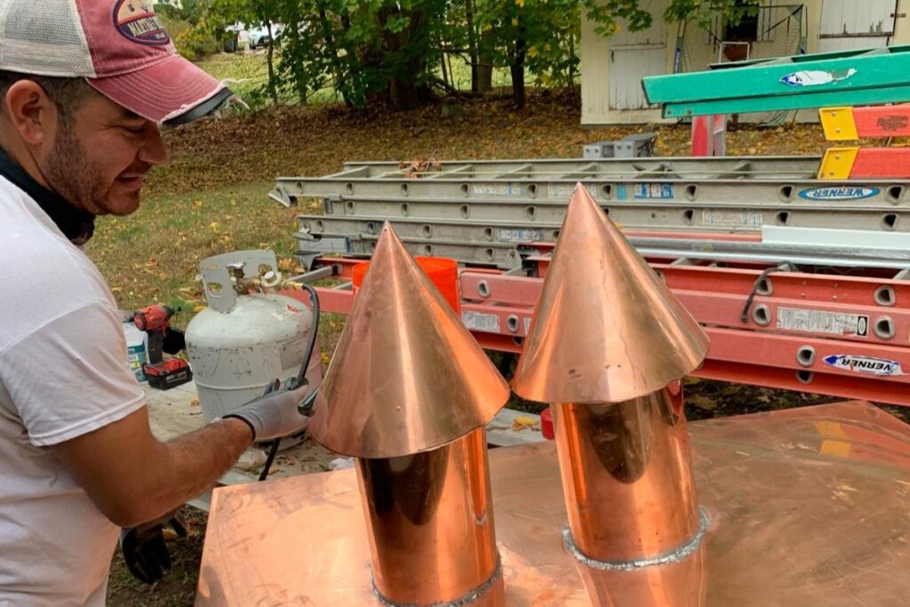 Master craftsman fabricating custom copper chimney cap for masonry chimney repair in Natick MA