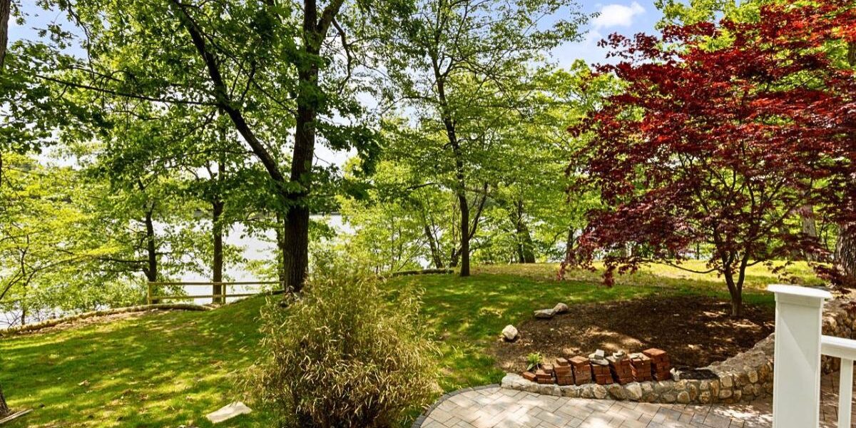 Custom stone paver patio and backyard landscape renovation overlooking a lake in Natick Massachusetts