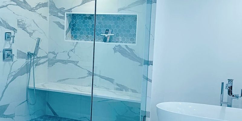 Modern master bathroom featuring a custom glass walk-in shower with marble tile, hexagonal accent niche, and freestanding tub