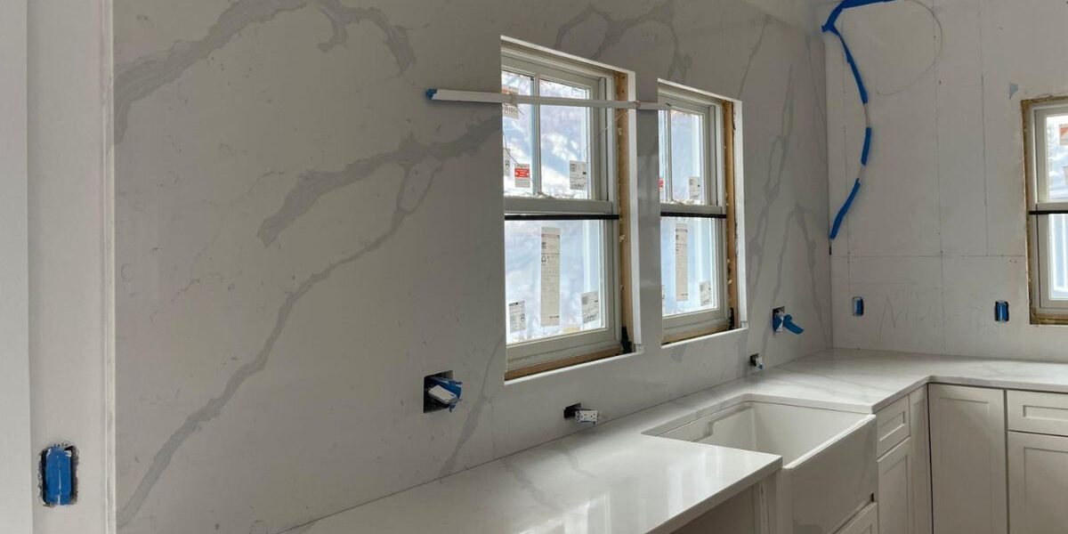 Custom quartz slab backsplash and apron farmhouse sink installation in luxury estate kitchen in Weston MA