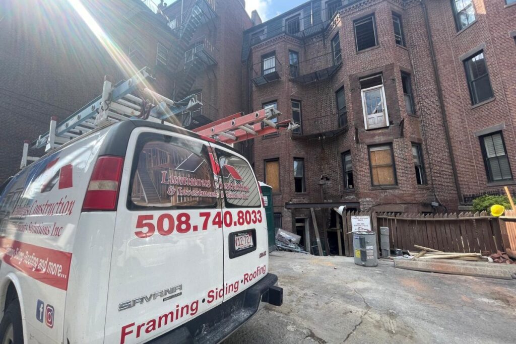 Luminous Construction service van on active historic multi-story brick building restoration site in Boston MA