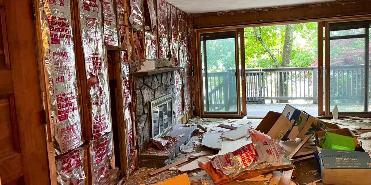 Living room gut renovation with exposed insulation framing and stone masonry fireplace in Newton MA