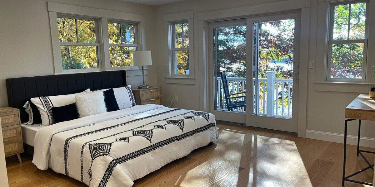 Spacious master suite renovation featuring hardwood floors, custom window trim, and balcony sliding doors in Natick MA
