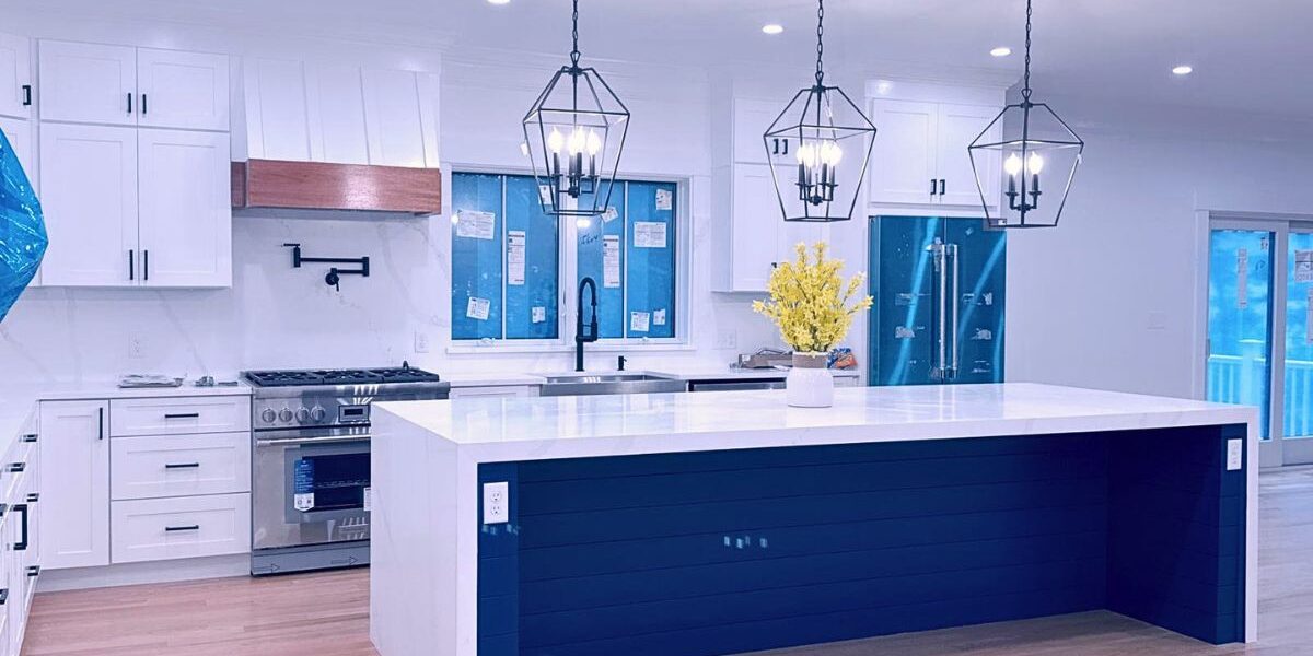 Custom kitchen remodel featuring a navy blue island with waterfall quartz countertop and geometric pendant lighting