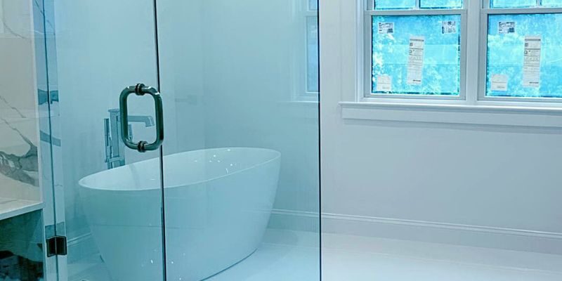 Luxury master bath remodel featuring a white freestanding soaking tub beside a frameless glass shower and Andersen window