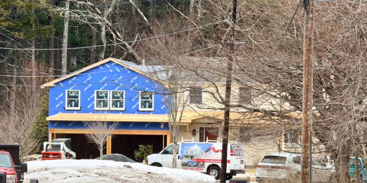 Luminous Construction van parked in front of home addition site with blue weather barrier in Newton MA