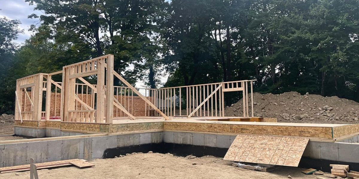 New residential construction site showing concrete foundation and custom wood framing in Massachusetts