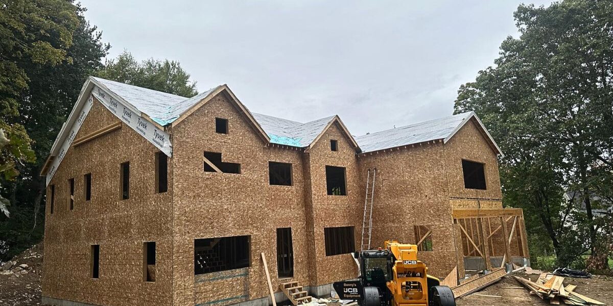 Large-scale custom home framing and roof underlayment installation project with JCB equipment in Sudbury MA
