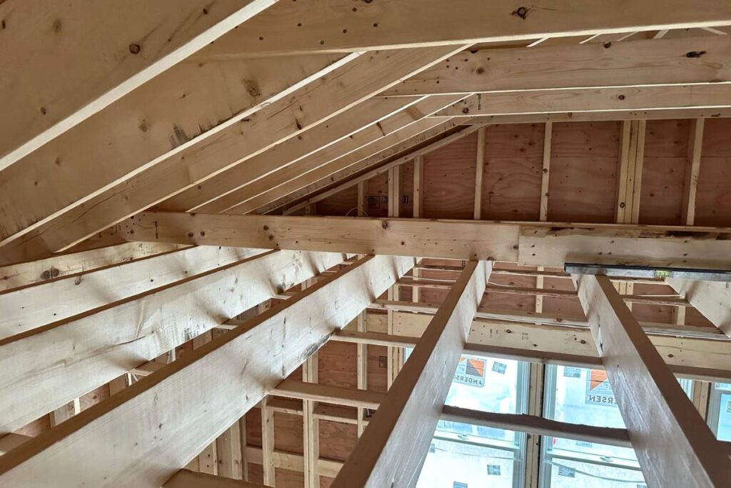 Interior view of engineered roof rafter framing, ridge beam, and plywood roof sheathing in Massachusetts home