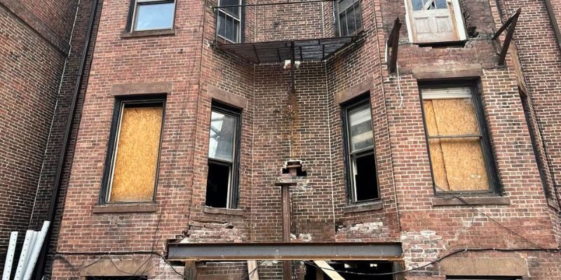 Multi-story brick historic brownstone building with exterior scaffolding setup for facade restoration in Boston